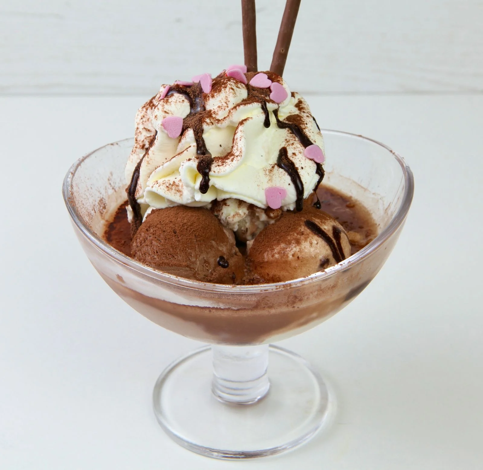 Schokoladen-Eisbecher mit Sahne, Kakao und Schokostäbchen